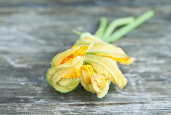 Italien, Toskana, Magliano, Nahaufnahme von Zucchini-Blume auf Holztisch — Stockfoto