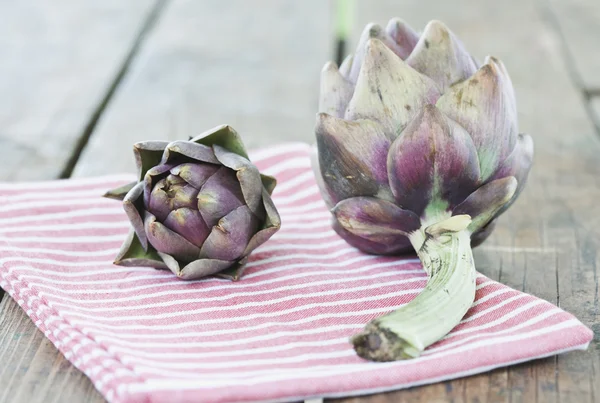 Italy, Tuscany, Magliano, Close up of artichokes with napkin on wooden table — ストック写真