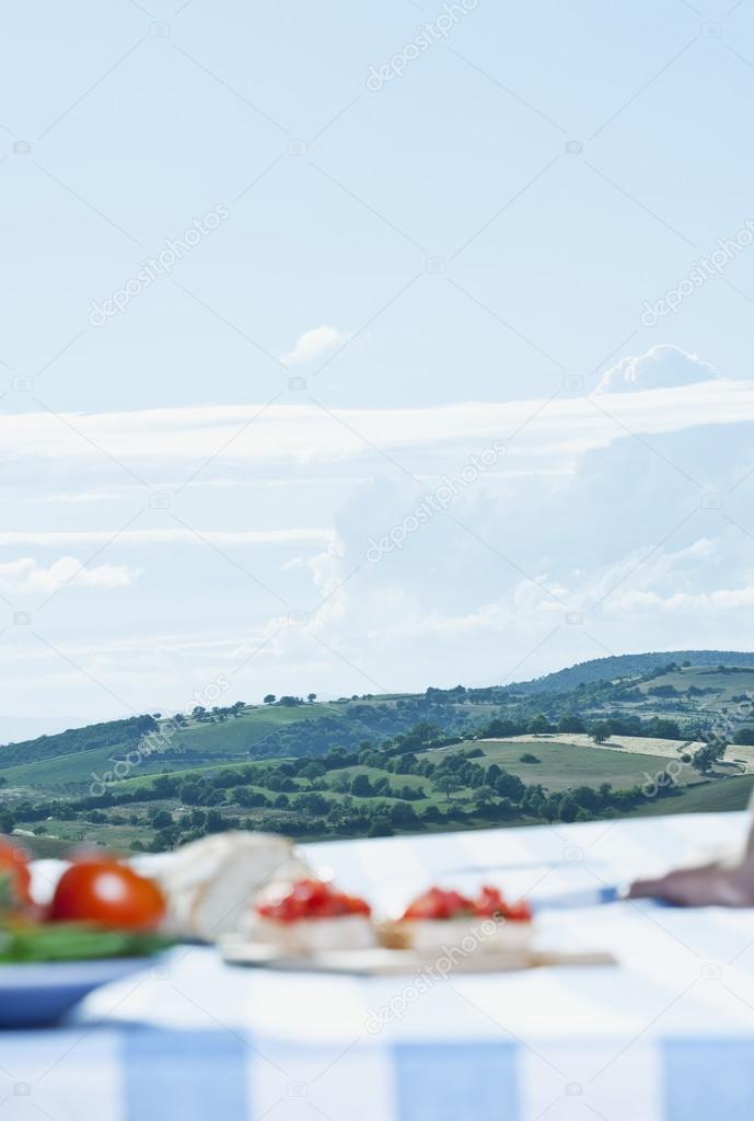 Italy, Tuscany, Magliano, Food on table with landscape in background
