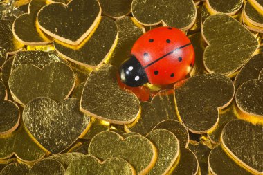 Ladybird figurine on golden hearts clipart