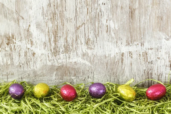 Ovos de chocolate coloridos na grama artificial — Fotografia de Stock