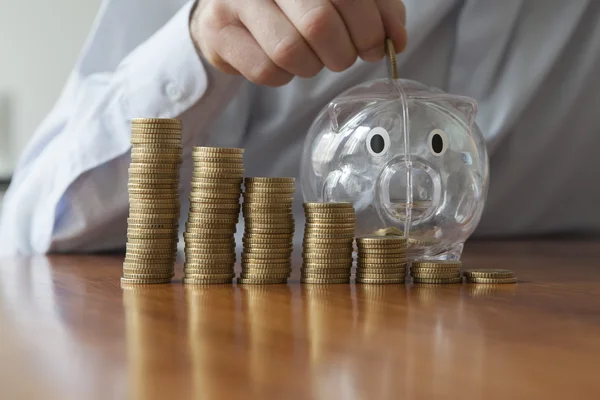 Hombre poniendo moneda en alcancía —  Fotos de Stock