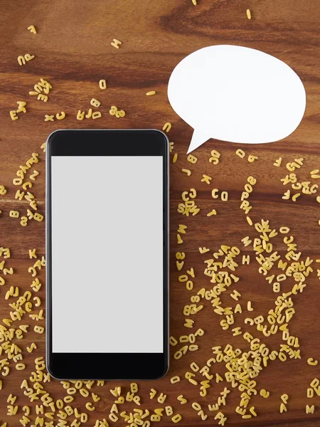 Smartphone on wood, alphabet noodles — Stock Photo, Image