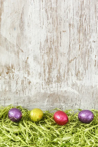 Ovos de chocolate coloridos na grama artificial — Fotografia de Stock