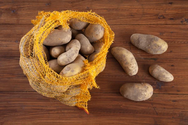 Картофель в сетке на дереве — стоковое фото