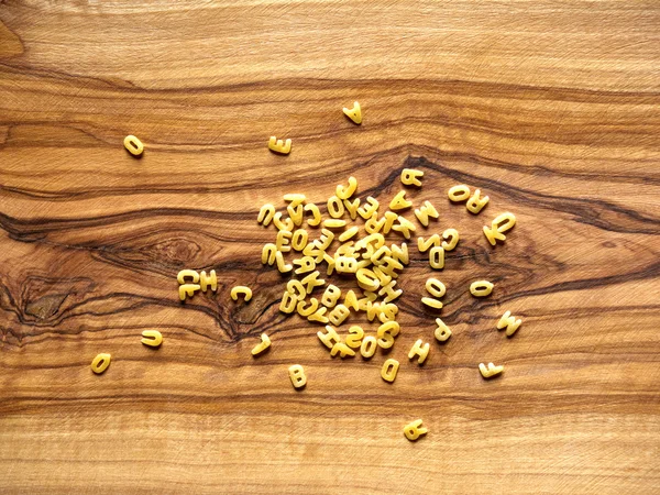 Alphabet noodles on wood — Stock Photo, Image