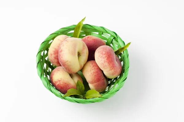 Doughnut peaches in green basket — Stock Photo, Image