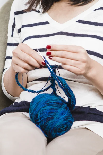 Young woman knitting blue scarf — Stock Photo, Image