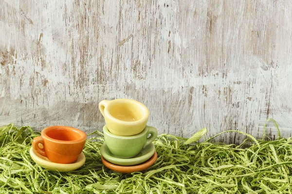 Miniature colorful cups on artificial grass — Stock Photo, Image