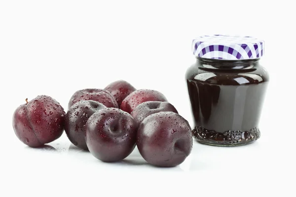 Plums beside jar of plum jam — Stock Photo, Image