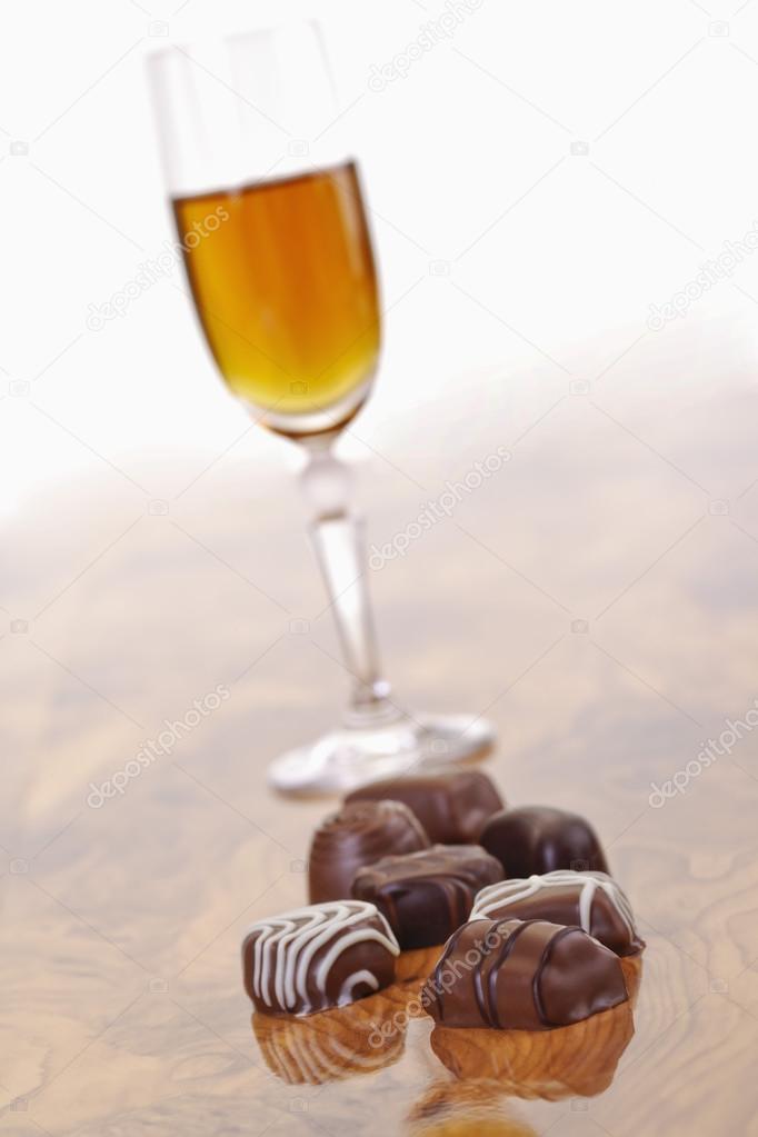 Pralines and glass of sherry on wood