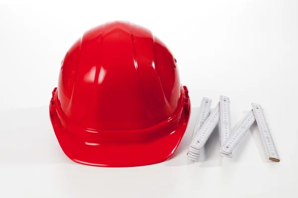 Red hardhat and folding ruler — Stock Photo, Image