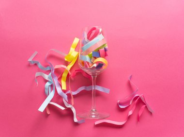 Pembe arka planda canlı kağıt konfetili şarap kadehi. Sanatsal.