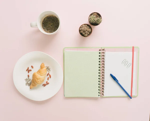 Modern kreatif kahve, kaktüs, defter ve ofis masasında taze kruvasan. Düz yatıyordu