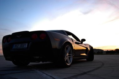 Gün batımı ışıklarının altında bir sahanın ortasında bir arabanın dikey görüntüsü.