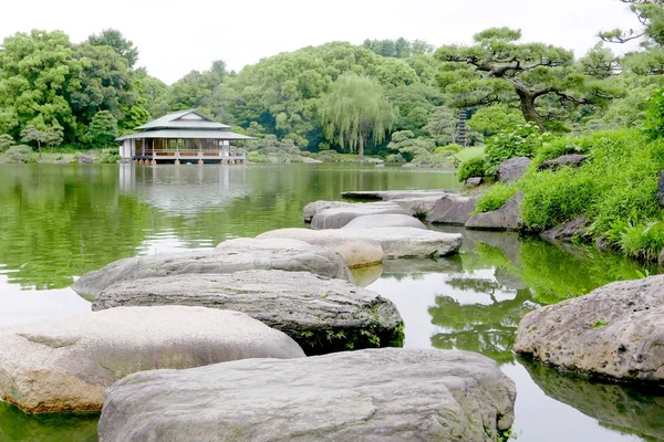 Ιαπωνικό περίπτερο κτίριο, πέτρινο γεφύρι, λίμνη νερού — Φωτογραφία Αρχείου