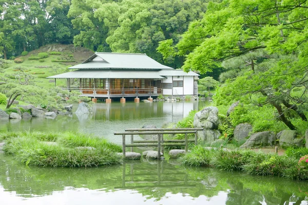 Ponte de pedra com reflexão e edifício pavilhão em jardim zen — Fotografia de Stock