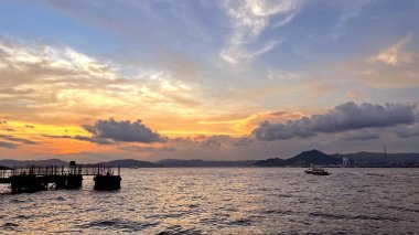 Yatay manzara fotoğrafı bazı tekneler, rıhtım, dağ, okyanus, gün batımında bulutlar