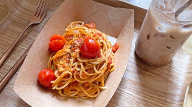 Klasik İtalyan yemeği spagettisi domatesli ve ahşap tepside buzlu kahve.