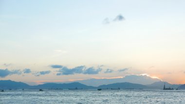 Mavi gökyüzü, beyaz bulutlar, günbatımı denizde sahil şeridi 