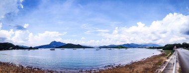 Tekneler, bulutlar, göl ve mavi gökyüzü