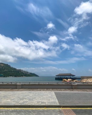 Güzel bir gün, açık mavi bir gökyüzü, okyanusun üzerinde kabarık beyaz bulutlar ve suyun üzerinde bir bina.