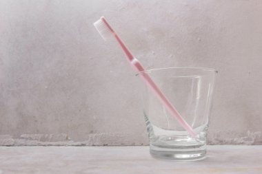Pembe diş fırçası ile beton arka plan şeffaf cam içinde