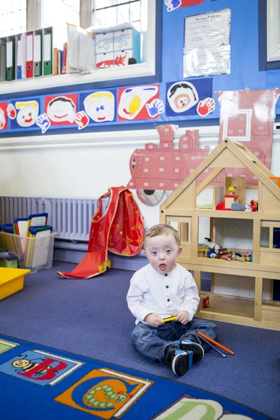 Синдром Дауна хлопчика в дитячій кімнаті — стокове фото