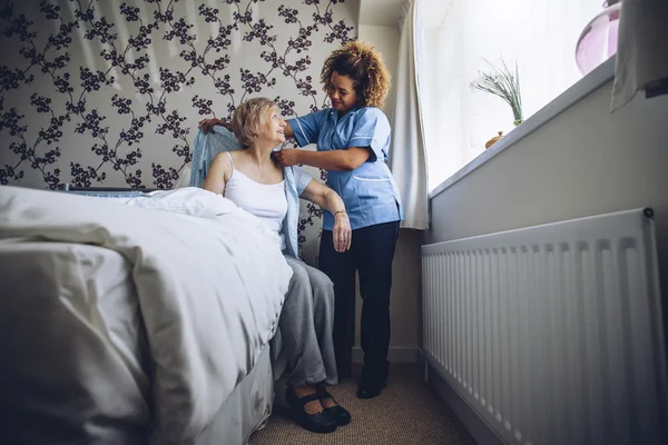 Home caregiver dressing senior — Stock Photo, Image