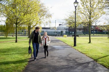 Kafkasyalı bir baba ve kızının okuldan eve birlikte yürürken çekilmiş bir fotoğrafı. El ele tutuşup gülümsüyorlar..