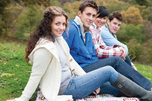 Four friends sit together outdoors and smile for the camera — Φωτογραφία Αρχείου