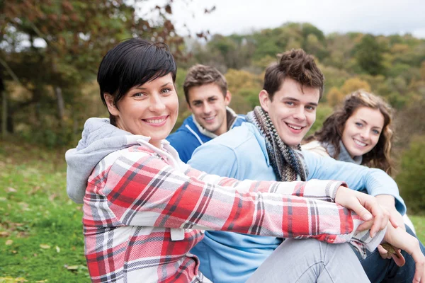 Four friends sit together outdoors and smile for the camera — Φωτογραφία Αρχείου