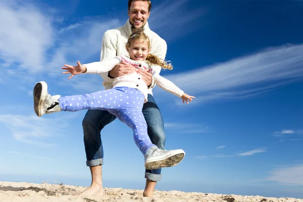 Отец размахивает дочерью на пляже — стоковое фото