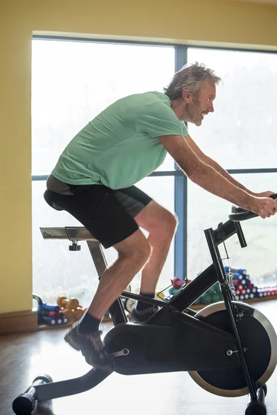 Homme âgé utilisant un vélo de spinning — Photo