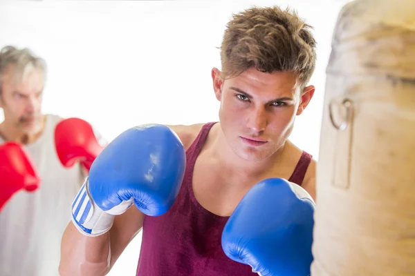 Jeune homme attrayant utilisant un sac de boxe — Photo