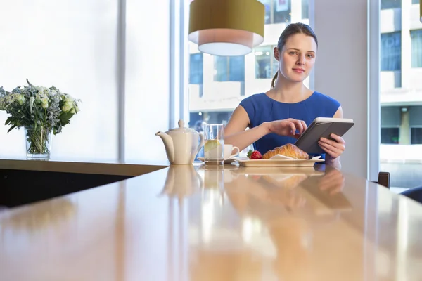 Wanita menggunakan tablet digital saat sarapan — Stok Foto