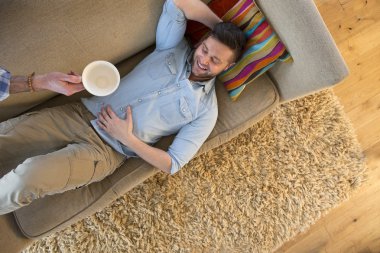 Male relaxing on sofa after coffee clipart