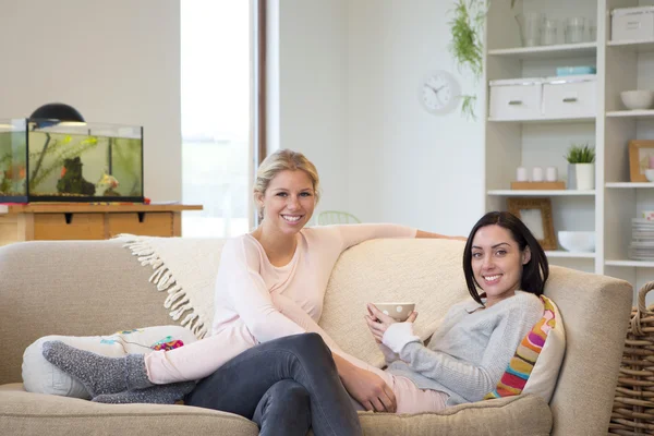 Couple féminin assis à la maison souriant pour la caméra — Photo