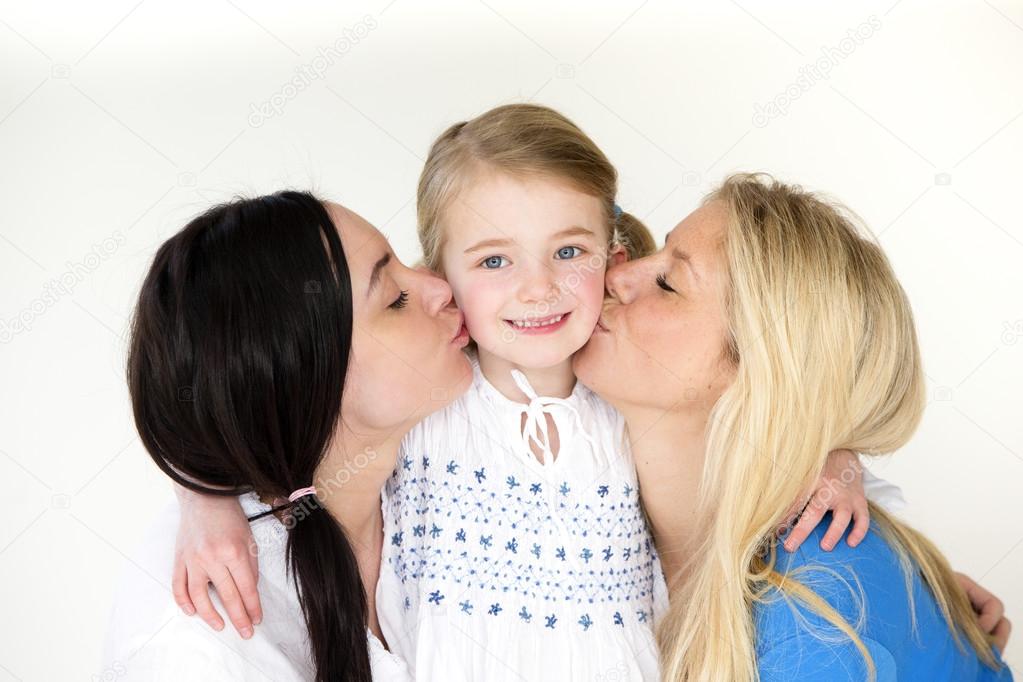 Female couple kissing daughters cheeks