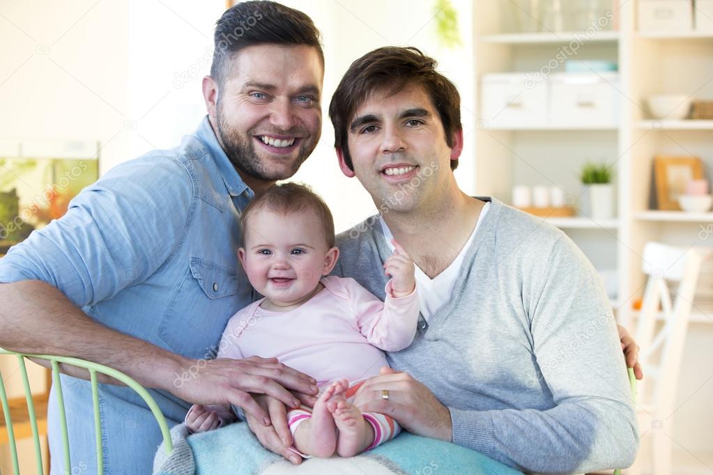 Male couple posing with their daughter at home