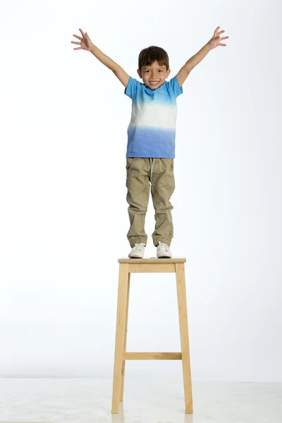 Menino de pé em um banco alto — Fotografia de Stock