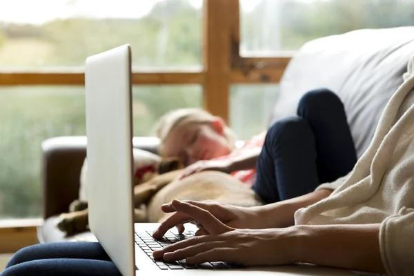 Mother using laptop whilst daughter sleeps — Stock Photo, Image