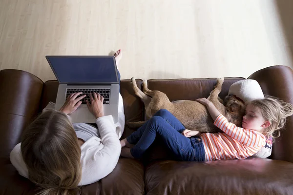 Mujer usando laptop mientras hija y perro duermen — Foto de Stock