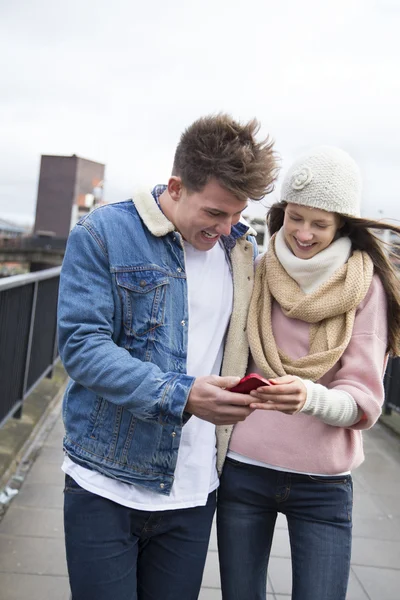 Couple walking in the city with a smartphone — Stock Photo, Image