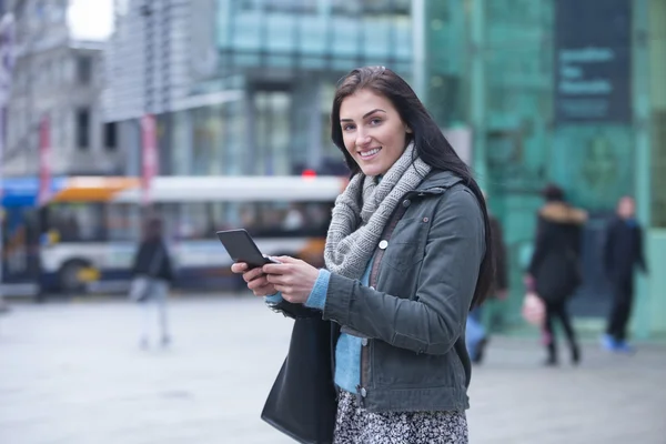 Ung kvinna i staden med en smartphone — Stockfoto