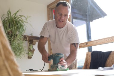 Bir masa yüzeyine bir zımpara kullanarak marangoz