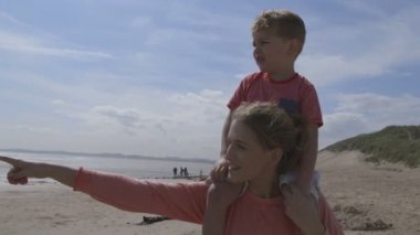 Genç anne ve oğul plaj boyunca yürüyüş