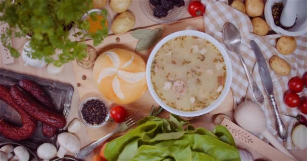 Sopa en cuenco en medio de varios ingredientes surtidos en mesa de madera — Vídeo de stock