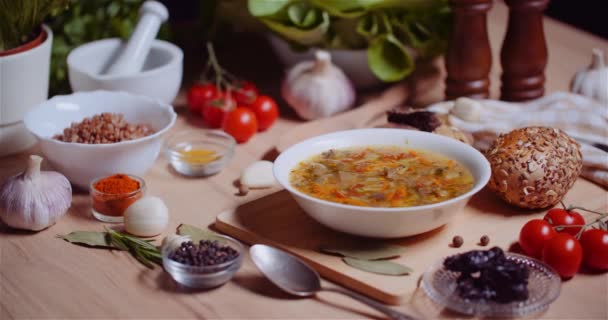 Zupa w misce wśród różnych składników Różnych posortowane na drewnianym stole — Wideo stockowe