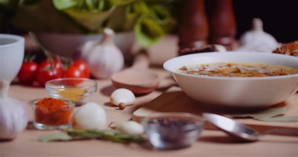 Σούπα στο μπολ ανάμεσα σε διάφορα συστατικά Ποικιλία σε ξύλινο τραπέζι — Αρχείο Βίντεο
